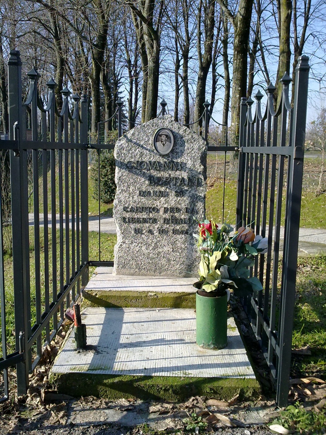 Cippo commemorativo dedicato a Giovanni Bertani, adornato da fiori e ornate da una recinzione.