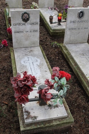 Tombe in marmo decorate con fiori artificiali, dedicate ai caduti per la Libertà, in un luogo di commemorazione.