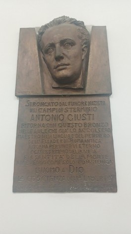 Lapide in bronzo con volto in rilievo di Antonio Giusti e iscrizione, affissa su parete chiara.