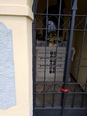 Cappella dei martiri di Trecella con altarini e fiori, immersa in un'atmosfera di commemorazione.