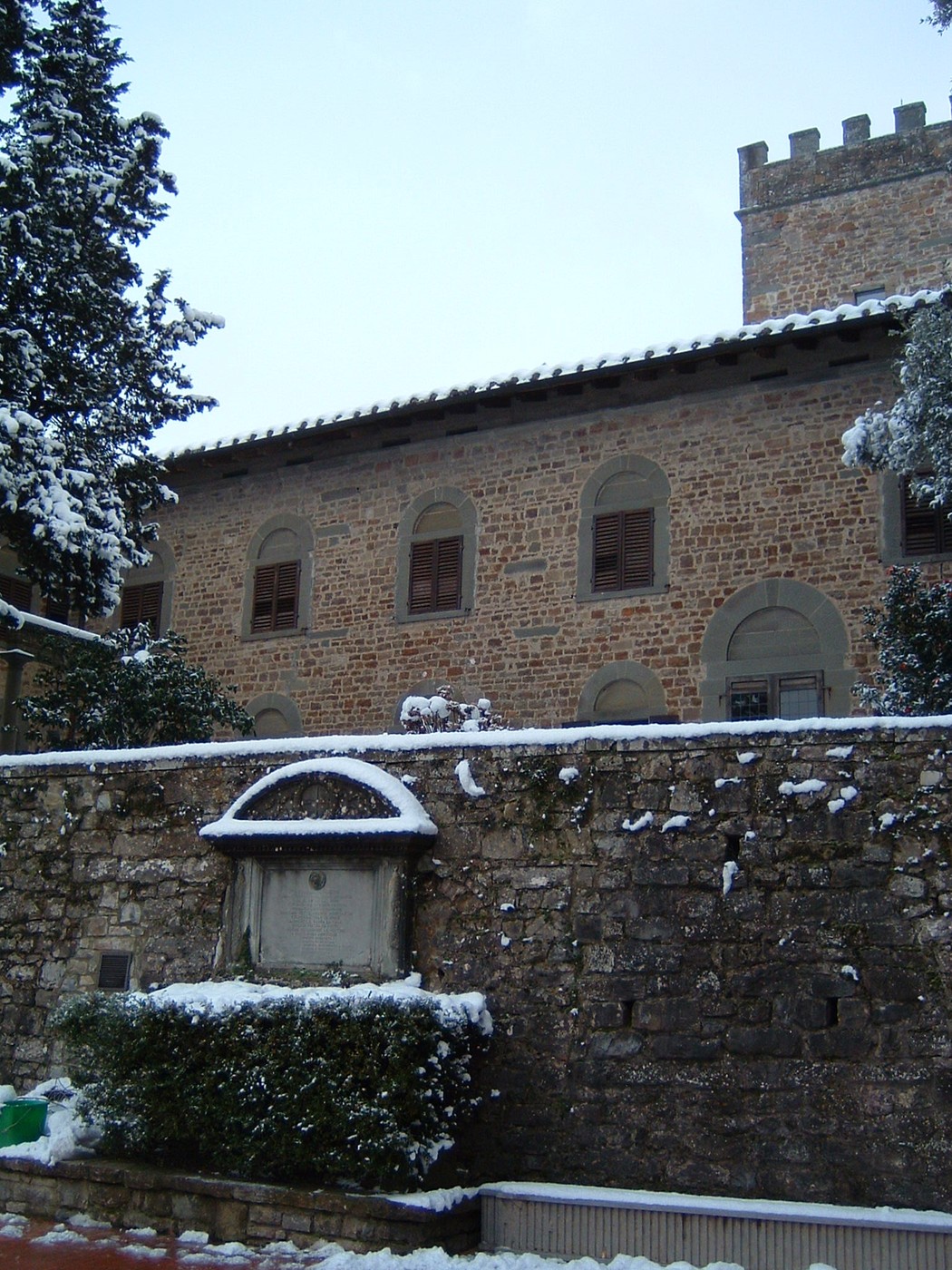 Lapide della fattoria di Querceto, incastonata in un muro di pietra, circondata da un paesaggio innevato.