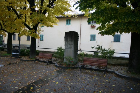 Monumento del ventennale, circondato da alberi e panchine, in un'atmosfera autunnale.