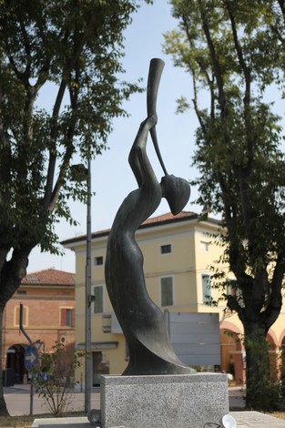 Monumento alle vittime del bombardamento, scultura evocativa tra alberi e edifici storici.