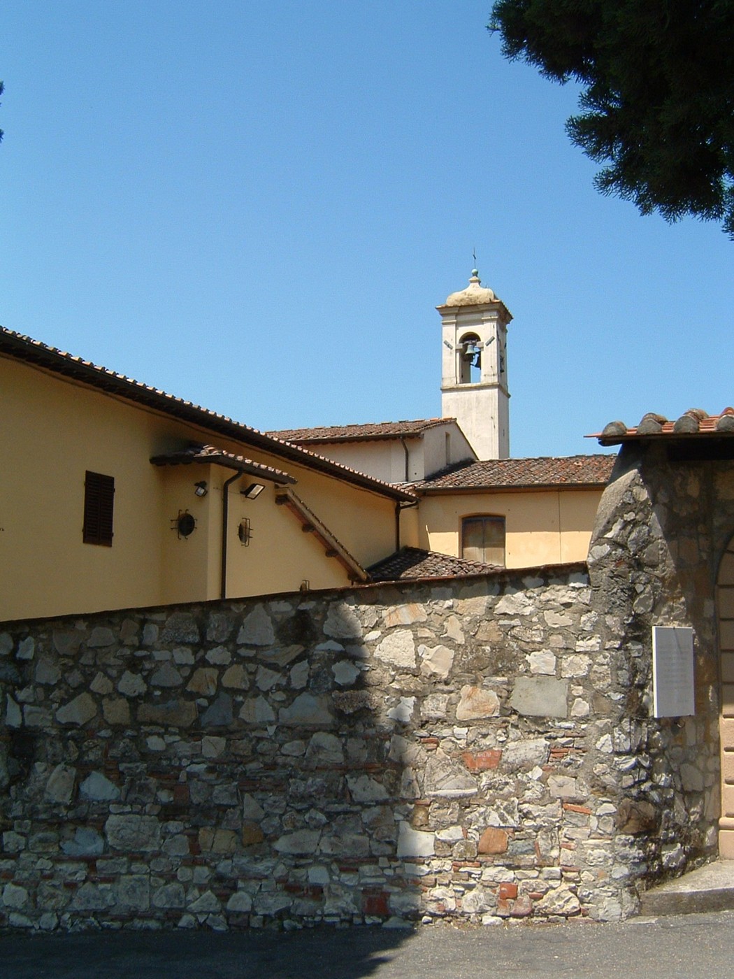 Lapide del convento di Santa Lucia in Castellina, visibile sul retro di un edificio storico con campanile.