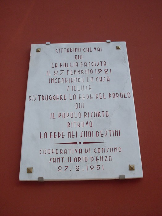 Lapide commemorativa che ricorda eventi storici legati alla cooperativa di consumo e alla resistenza popolare.