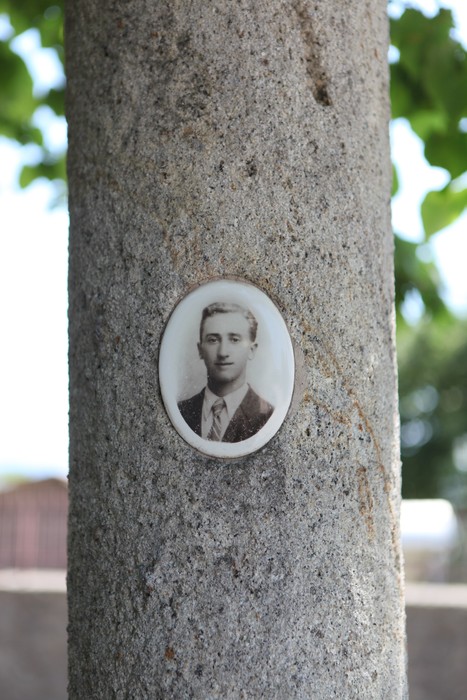 Monumento commemorativo con fotografia storica incastonata in una colonna di pietra.