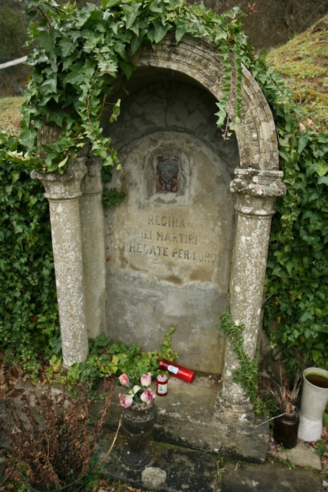 Monumento dell'Orenaccio, dedicato ai martiri, adornato da edera e fiori, immerso nella natura.