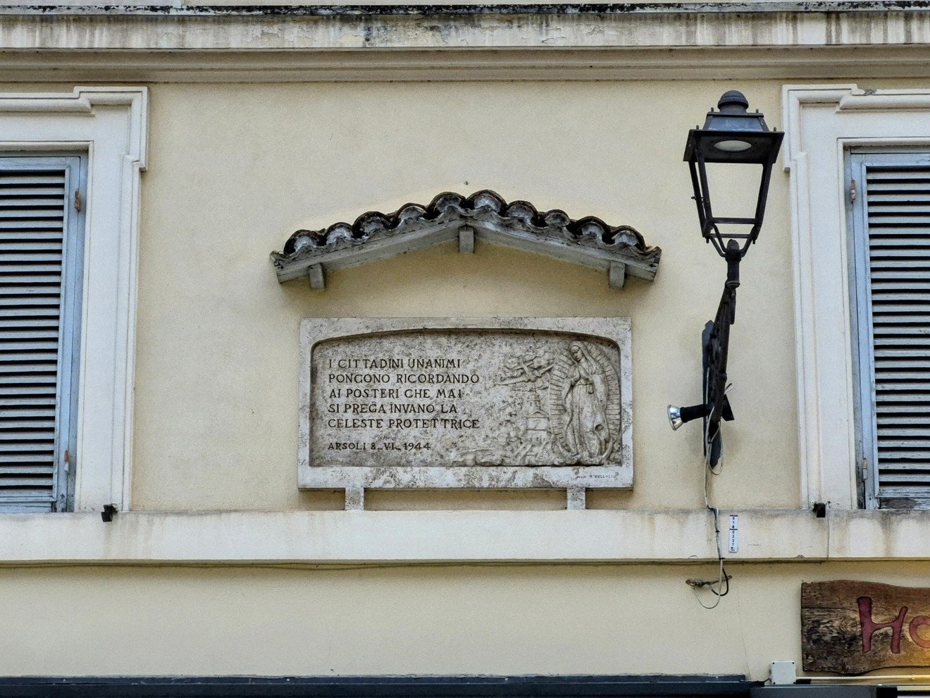 Lapide di ringraziamento alla Madonna su una facciata, ornata e ben conservata, sotto una lanterna.
