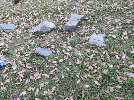 Il Monumento ai caduti della Liberazione circondato da foglie secche e pietre tombali in un ambiente naturale.