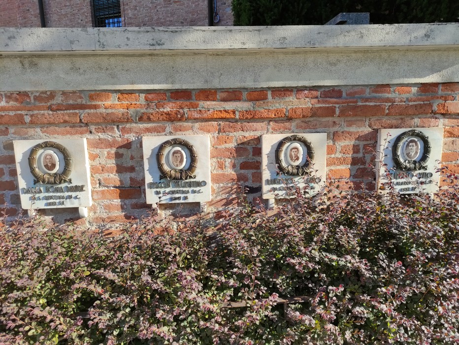 Monumento commemorativo per le vittime dell'eccidio di Santa Giustina in Colle, incastonato in un muro di mattoni.