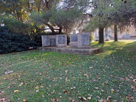 Monumento ai Caduti immerso nel verde, composto da lastre in pietra dedicate ai caduti della guerra.
