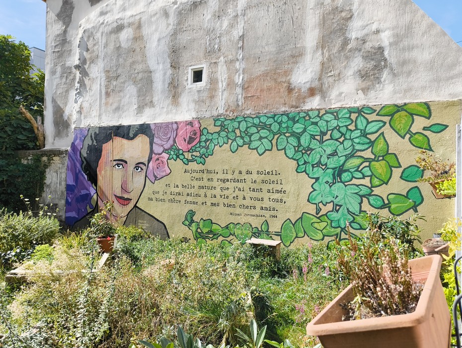 Murales dedicato al Gruppo Manouchian, simbolo della Resistenza, tra colori vivaci e natura.