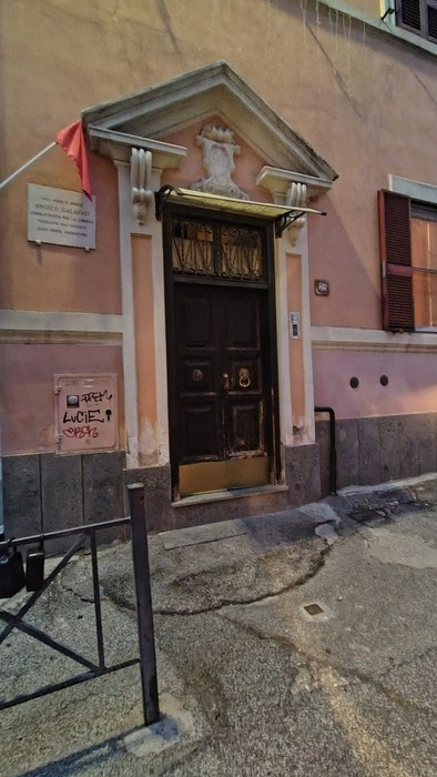 Entrata di una casa con porta in legno e decorazioni, muratura colorata e dettagli architettonici.