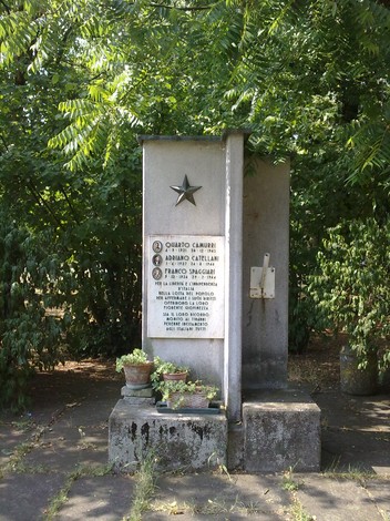 Monumento commemorativo a Camurri, Catellani e Spaggiari, immerso nel verde, con lapide e decorazioni.