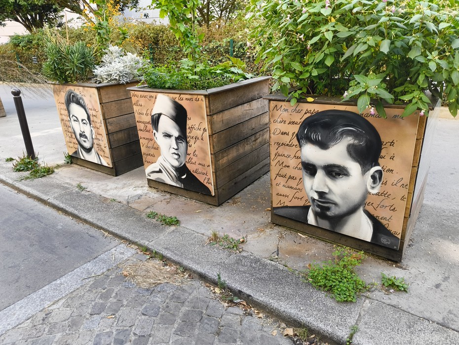 Rappresentazione artistica dedicata al Gruppo Manouchian, con volti su contenitori in legno.