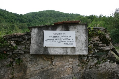 Lapide commemorativa di Gino Lombardi e dei partigiani della Valsesia, situata in un'area verdeggiante.