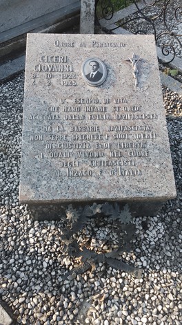 Lapide in memoria di Giovanni Ciceri, con decorazioni e un messaggio commemorativo. Giardino circostante.