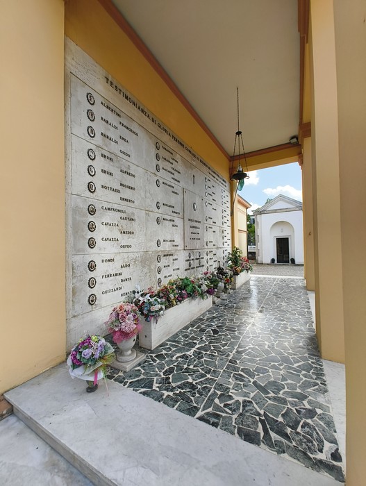 Sacrario dei Caduti Partigiani, con monumento e fiori commemorativi in un ambiente sobrio e rispettoso.
