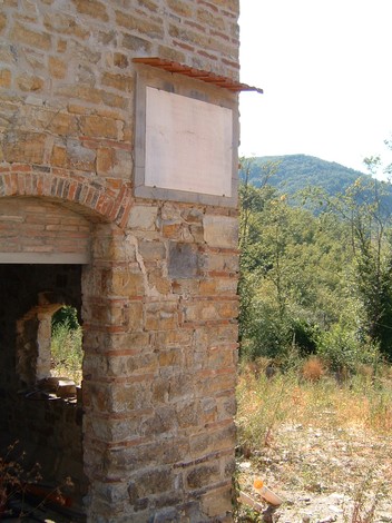 Lapide di Morlione, monumento in pietra, immerso nella natura e parte di una costruzione storica.