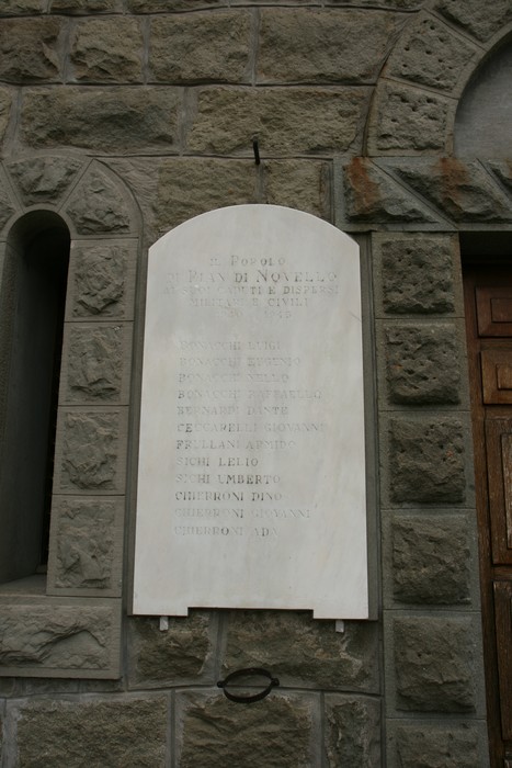Lapide commemorativa dedicata ai caduti di Pian di Novello, situata su una parete di pietra.