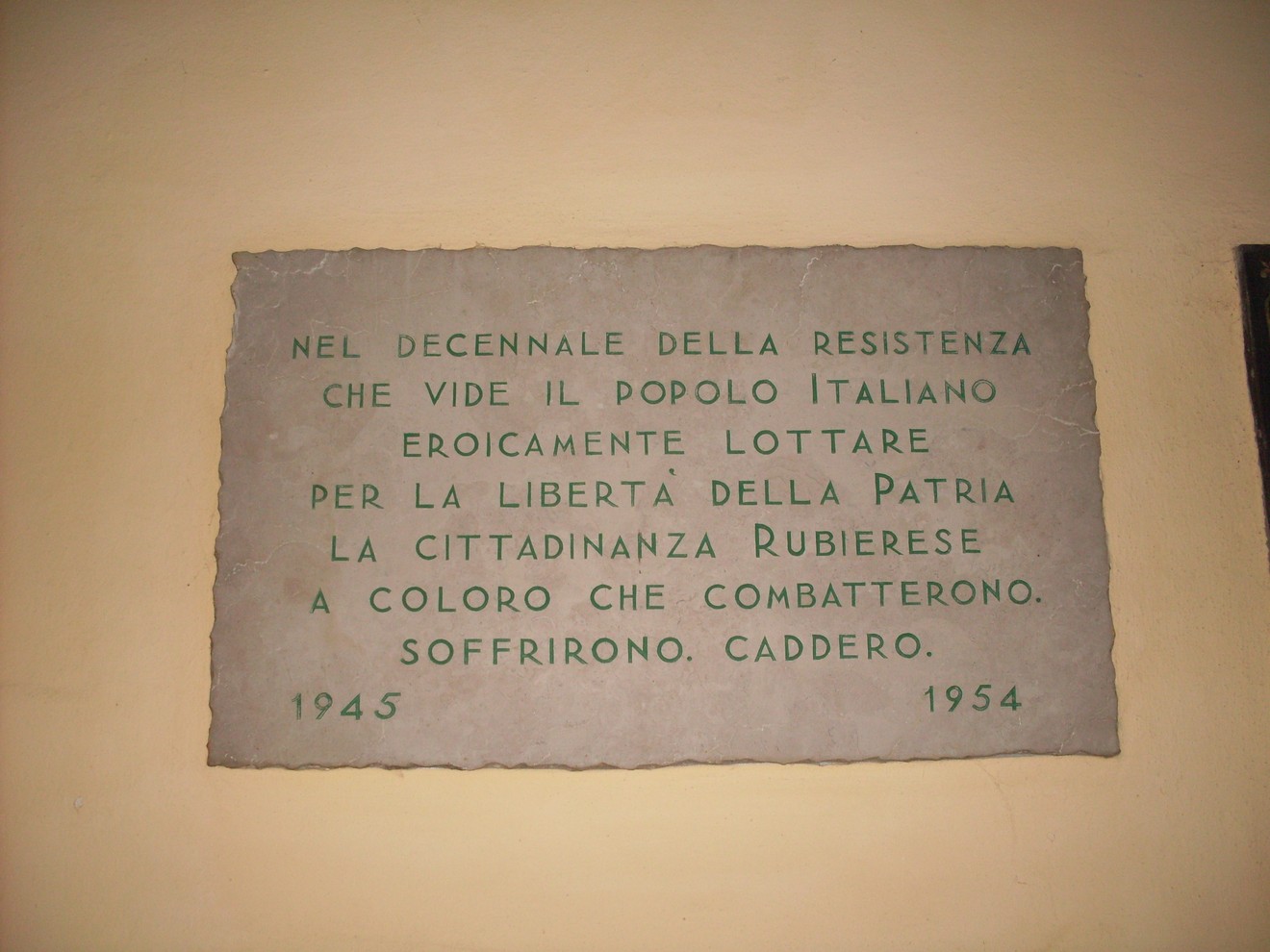 Lapide commemorativa che celebra il decennale della Resistenza italiana, onorando i combattenti e la libertà.