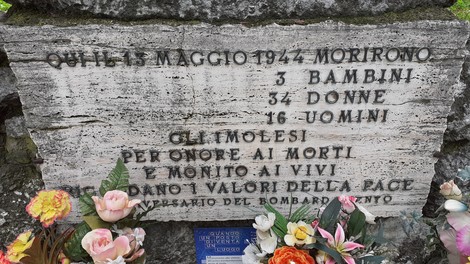 Monumento commemorativo alle vittime del bombardamento su Imola, con iscrizione e fiori in memoria dei caduti.