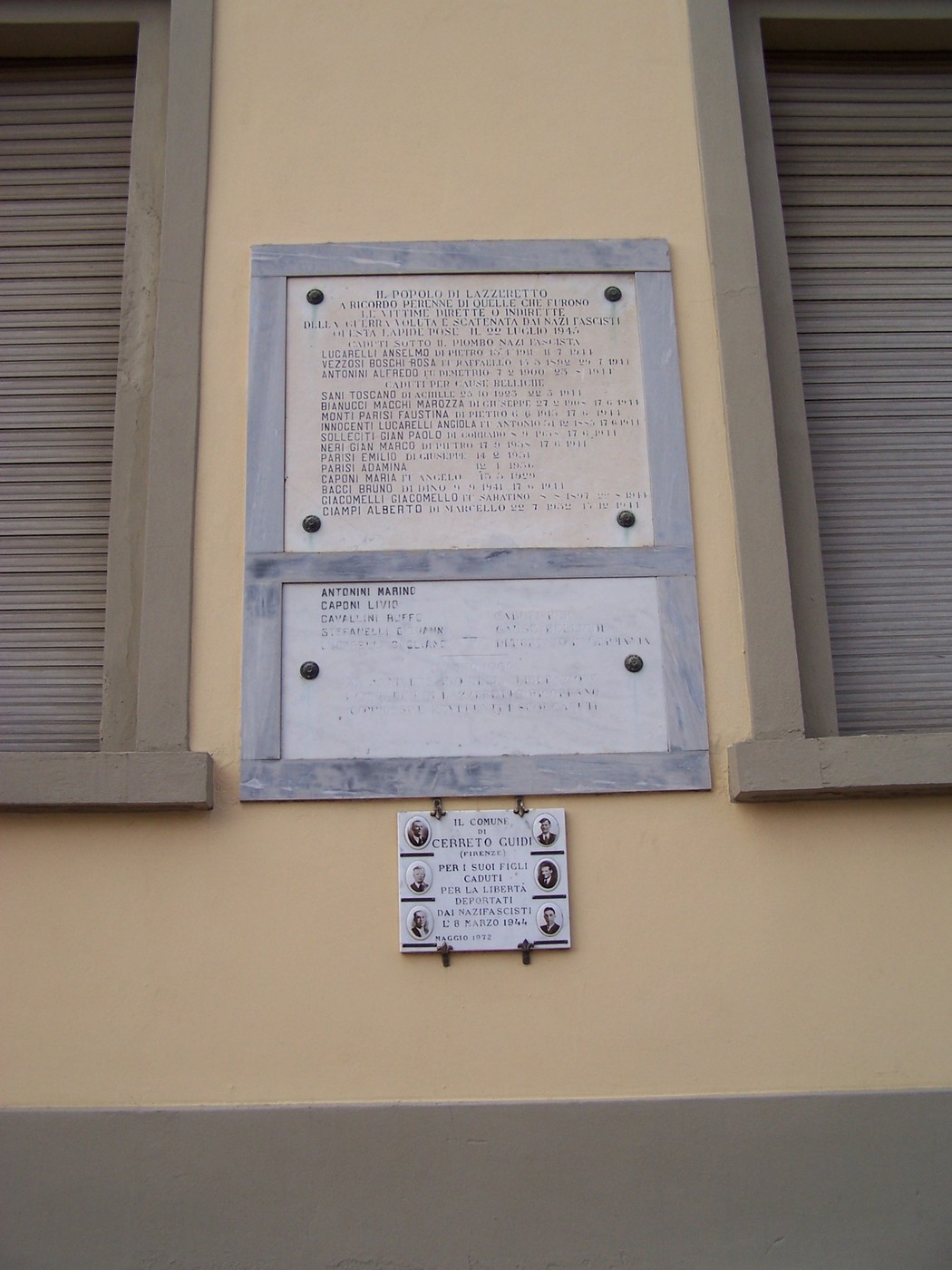 Lapide commemorativa che onora i caduti in conflitti bellici, situata su un edificio.