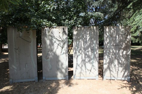 Monumento ai Martiri del Panaro, composto da quattro lastre di pietra tra alberi e ombre nel parco.