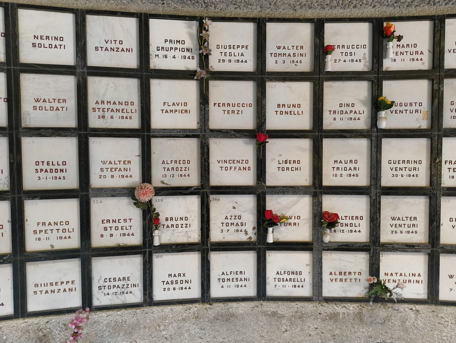 Monumento Ossario dei caduti partigiani, con nomi incisi e fiori in memoria dei combattenti.