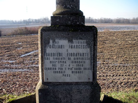 Cippo commemorativo dedicato a Pogliani Francesco e Barbieri Fioravante, situato in un campo aperto.