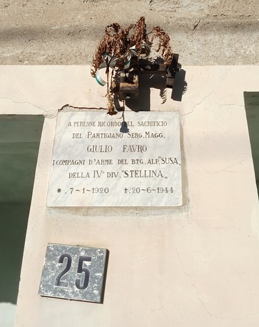 Lapide commemorativa dedicata al partigiano Giulio Favro, appesa a un muro con un numero civico.