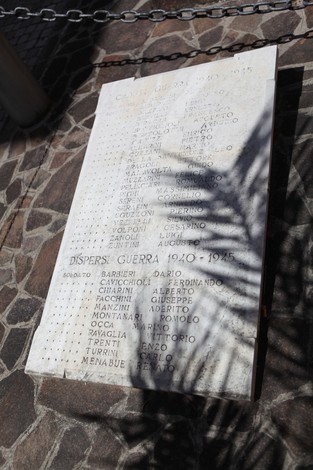 Monumento ai Caduti con lista di nomi in memoria dei dispersi nella guerra 1915-1918. Atmosfera solenne e rispettosa.