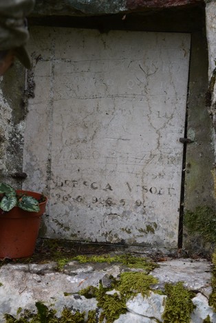 Cippo commemorativo dedicato a Pelizzari, immerso nella natura circostante.