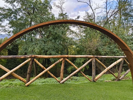 Percorso panoramico con arco in legno, immerso nel verde e affacciato su un paesaggio naturale.