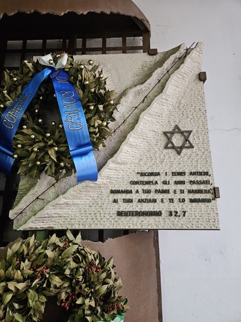 Monumento alla Shoah con dedica commemorativa e simbolo della Stella di David. Decorato con ghirlande e nastro.