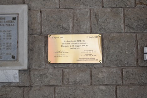 Lapide commemorativa con targa dedicata ai martiri, collocata su una parete di pietra.