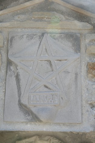 Dettaglio del "Tabernacolo di Valdonetto" con simbolo e incisioni su pietra. Architettura storica locale.