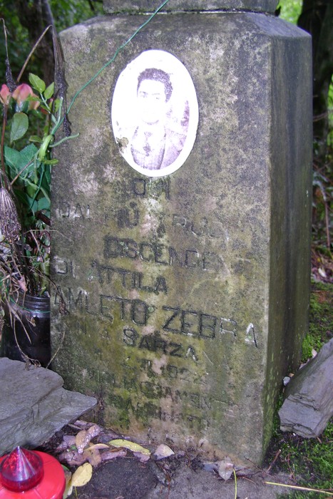 Cippo commemorativo in memoria di Amleto Zebra, con foto e iscrizioni su una parete di pietra.