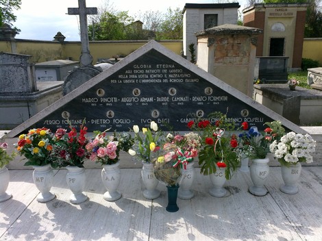 Monumento commemorativo ai caduti di Massenzatico, adornato da fiori e iscrizioni in memoria dei defunti.
