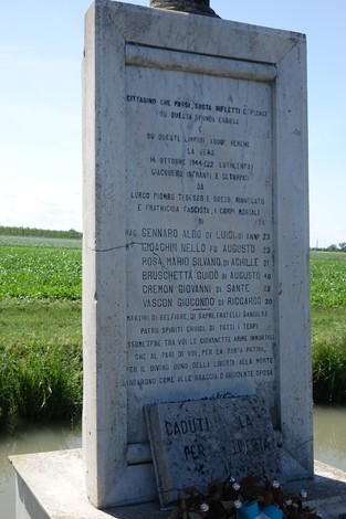 Cippo commemorativo dedicato a Gennaro e altri, situato in un paesaggio rurale.