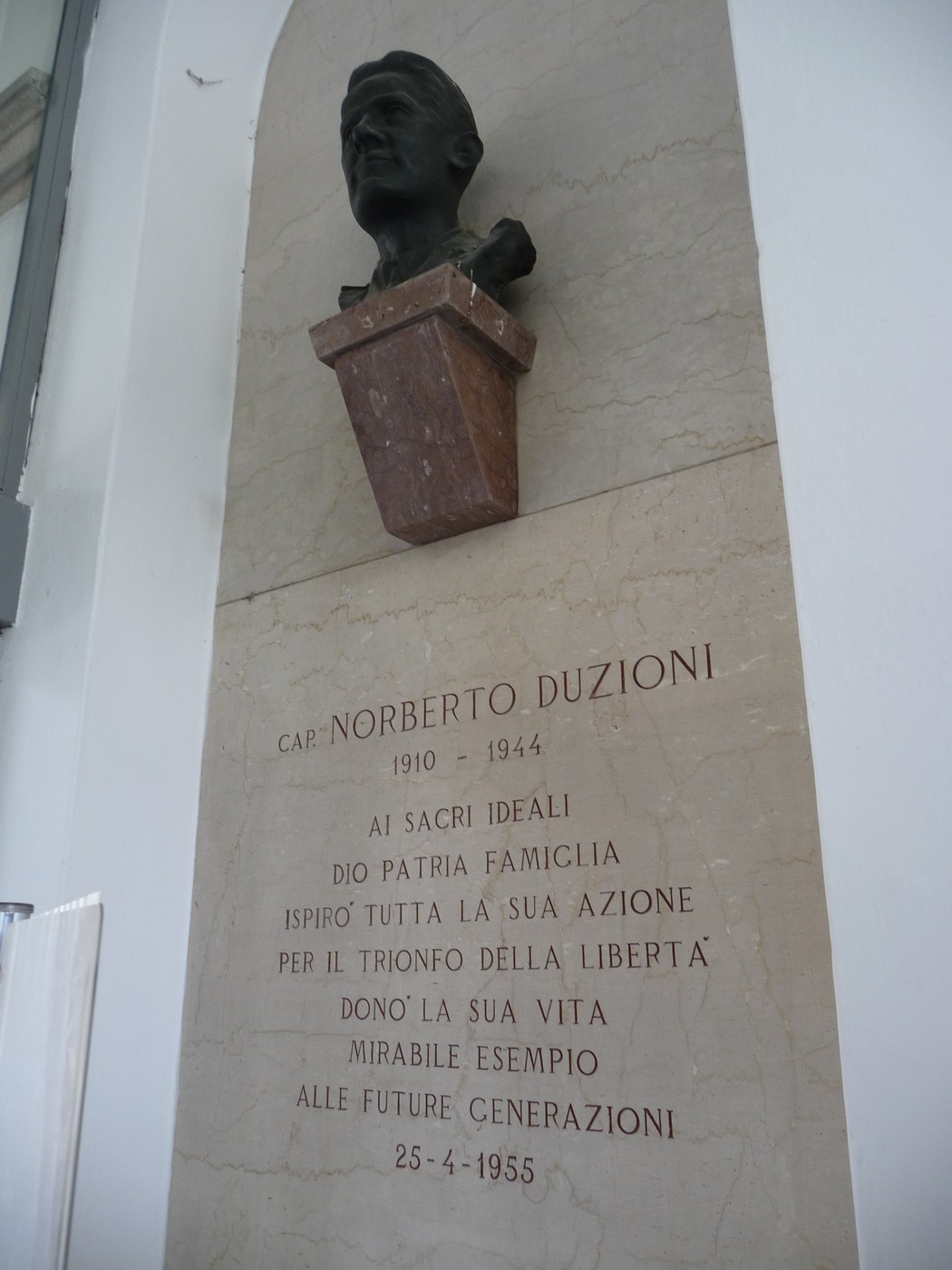 Lapide commemorativa di Norberto Duzioni con busto, dedicata ai suoi ideali e alla futura generazione.