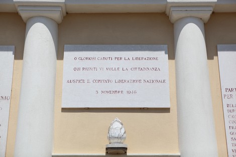 Sacrario dei Caduti per la Liberazione, con iscrizioni commemorative su una parete e colonne bianche.