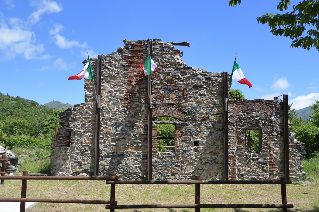 Rovine della Benedicta: affascinanti resti storici immersi nella natura, con bandiere italiane che sventolano.