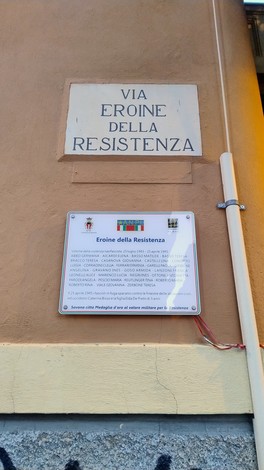Targa commemorativa dedicata alle donne della Resistenza, con informazioni storiche e nome della via.