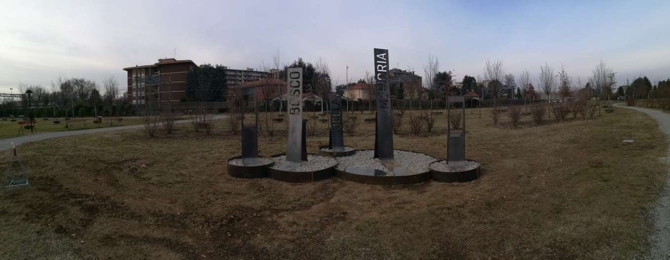 Monumento "Bosco della Memoria" con pilastri commemorativi immersi in un'area verde tranquilla.