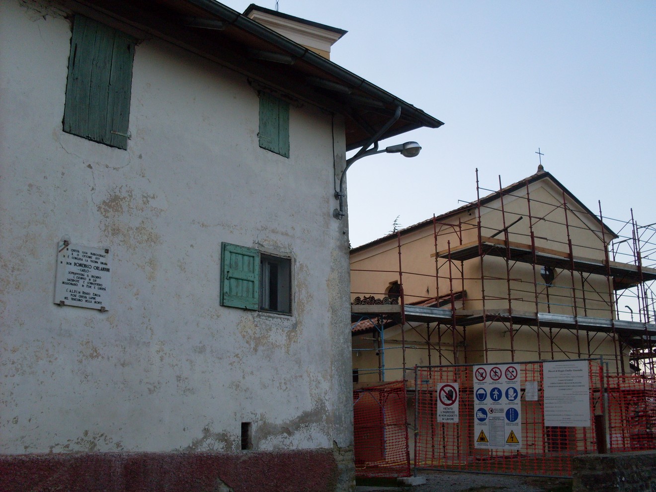 Lapide commemorativa dedicata a Orlandini, visibile su un edificio storico in fase di restauro.