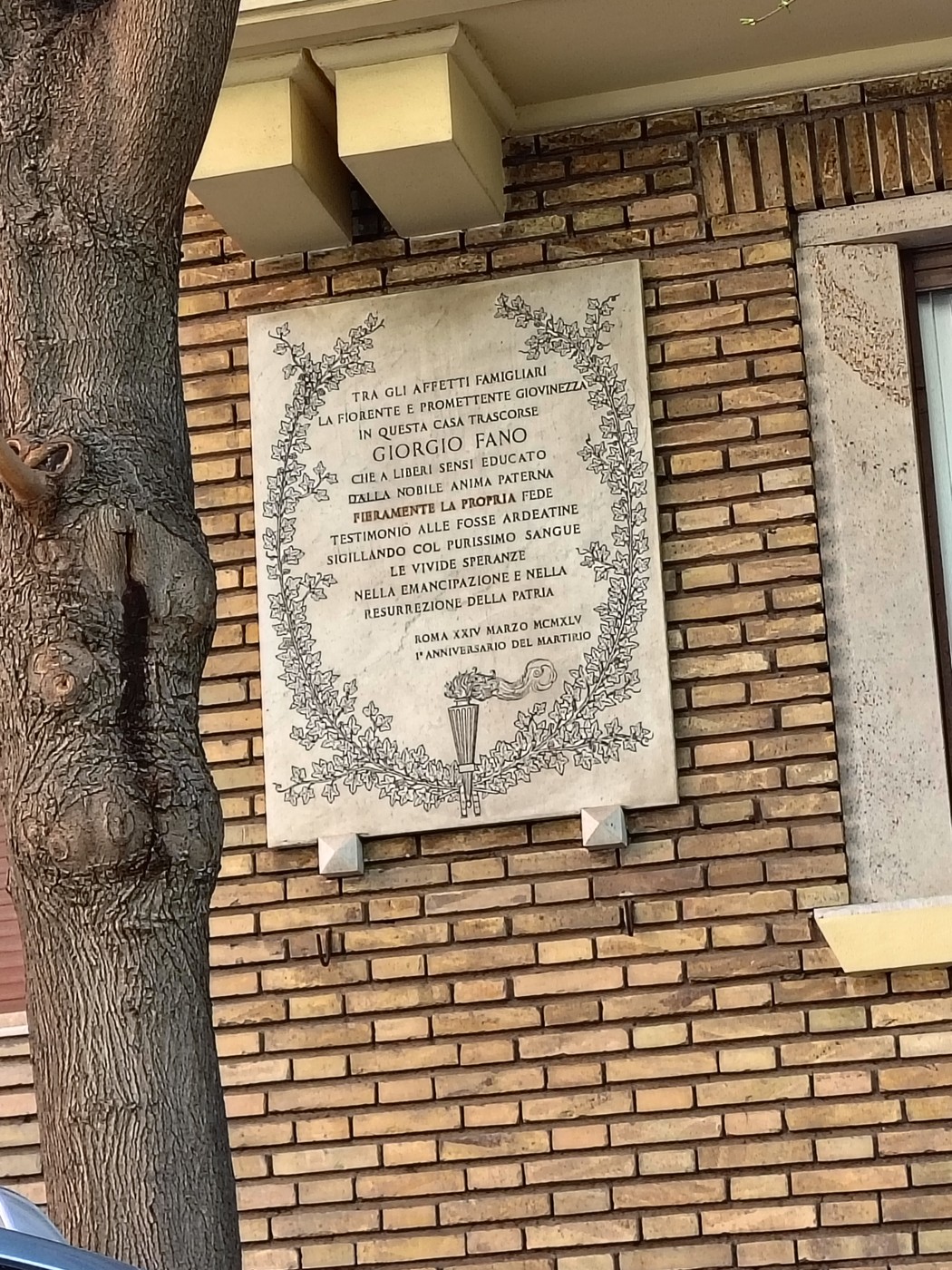 Lapide commemorativa a Fano, con iscrizioni storiche su un muro di mattoni.