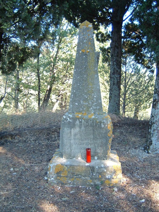 Cippo commemorativo presso la Cappella di San Vincenzo, circondato da alberi in un'area tranquilla.