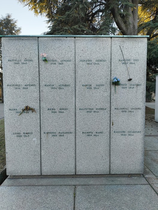 Monumento commemorativo al "Campo della Gloria" con lapidi in pietra e decorazioni floreali.