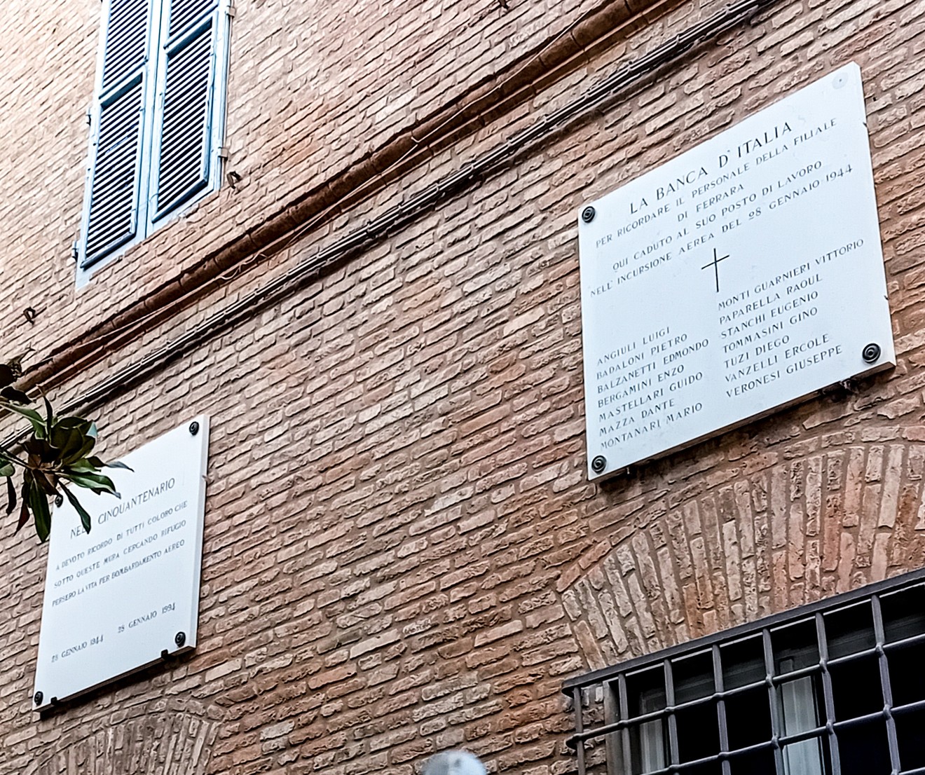 Lapidi commemorative alle vittime del bombardamento della Banca d'Italia, su muro di mattoni in una città storica.